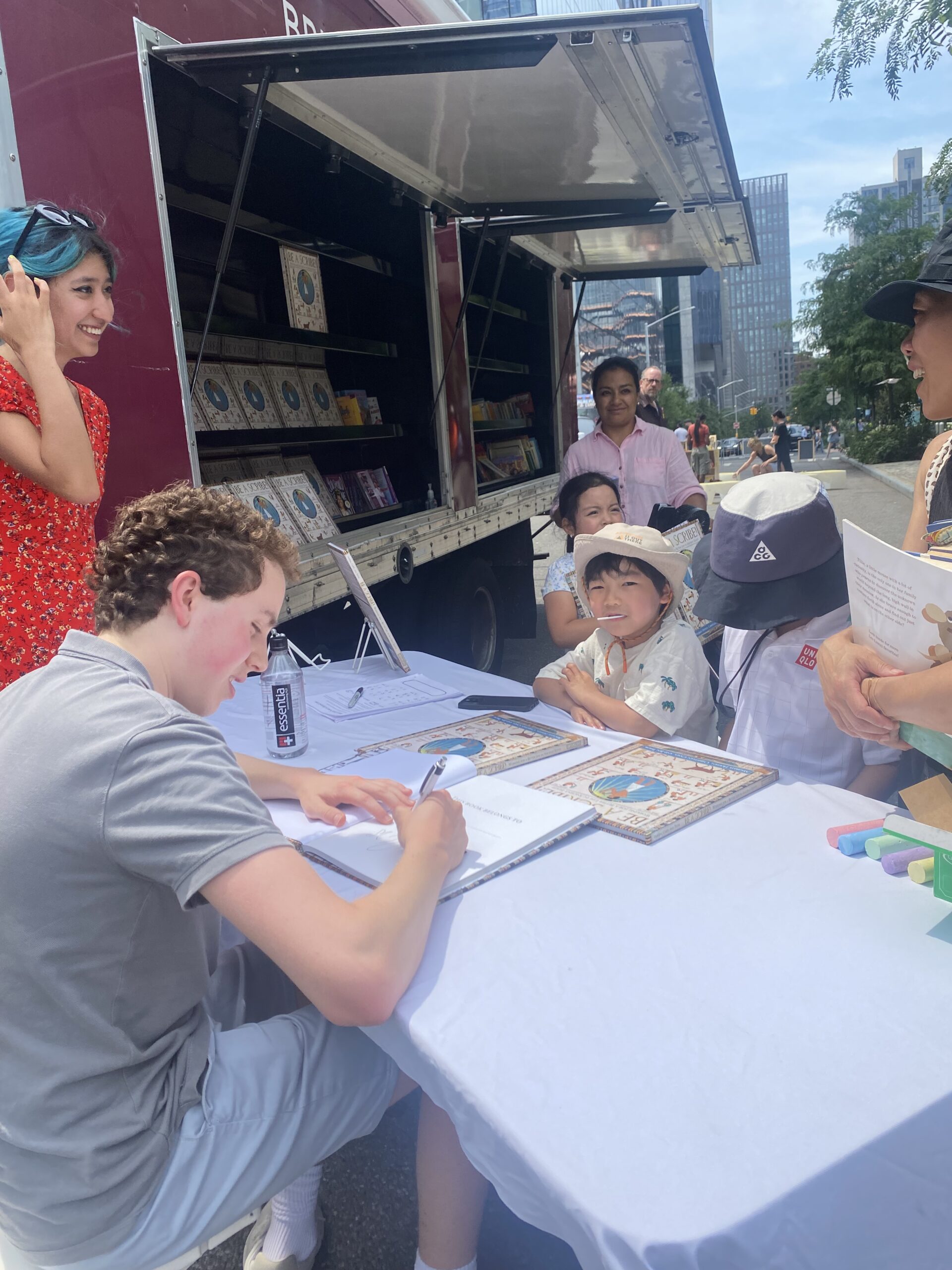 A crowd of young children gathers around House of SpeakEasy's Bookmobile